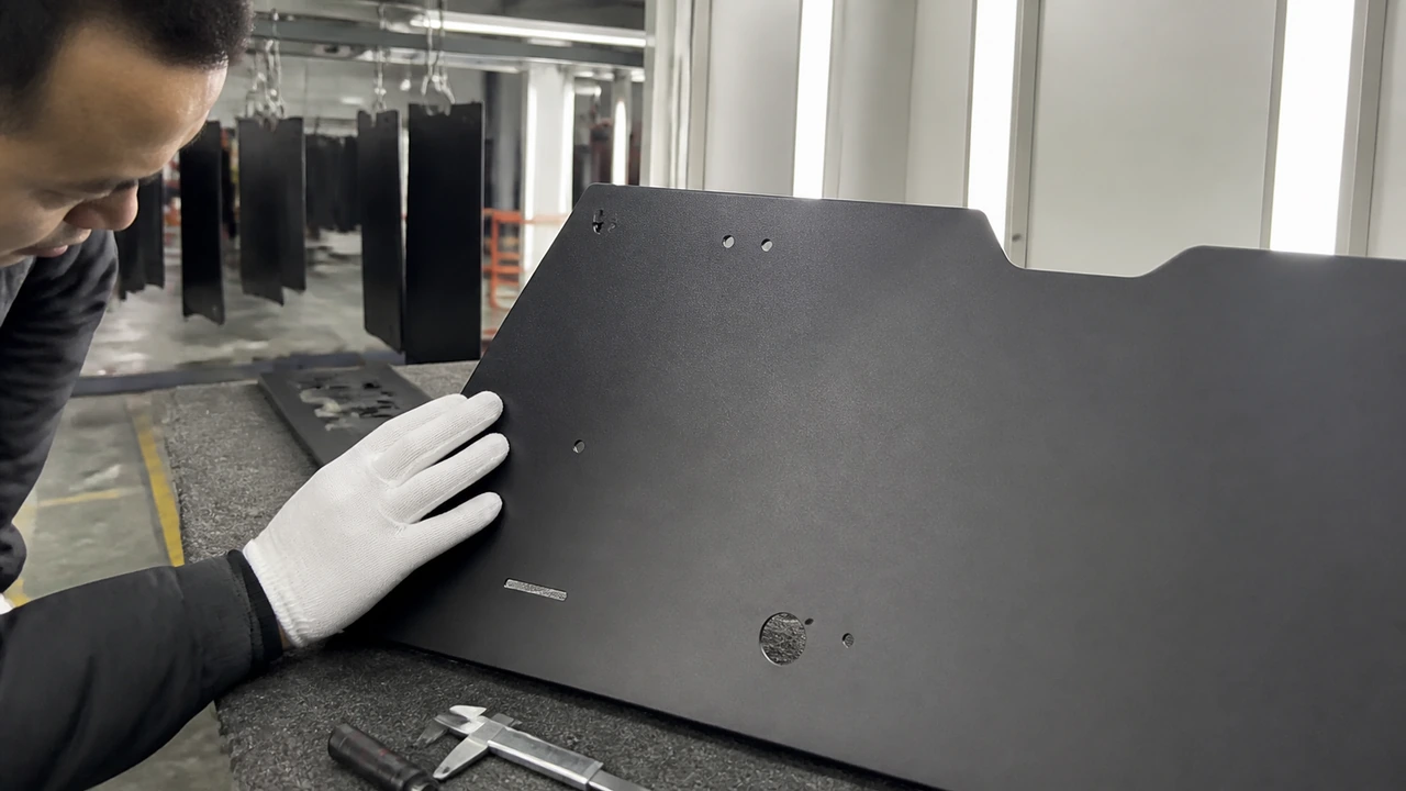 Quality control specialist inspecting matte black electrostatic powder coating finish and corner paint adhesion under neutral light